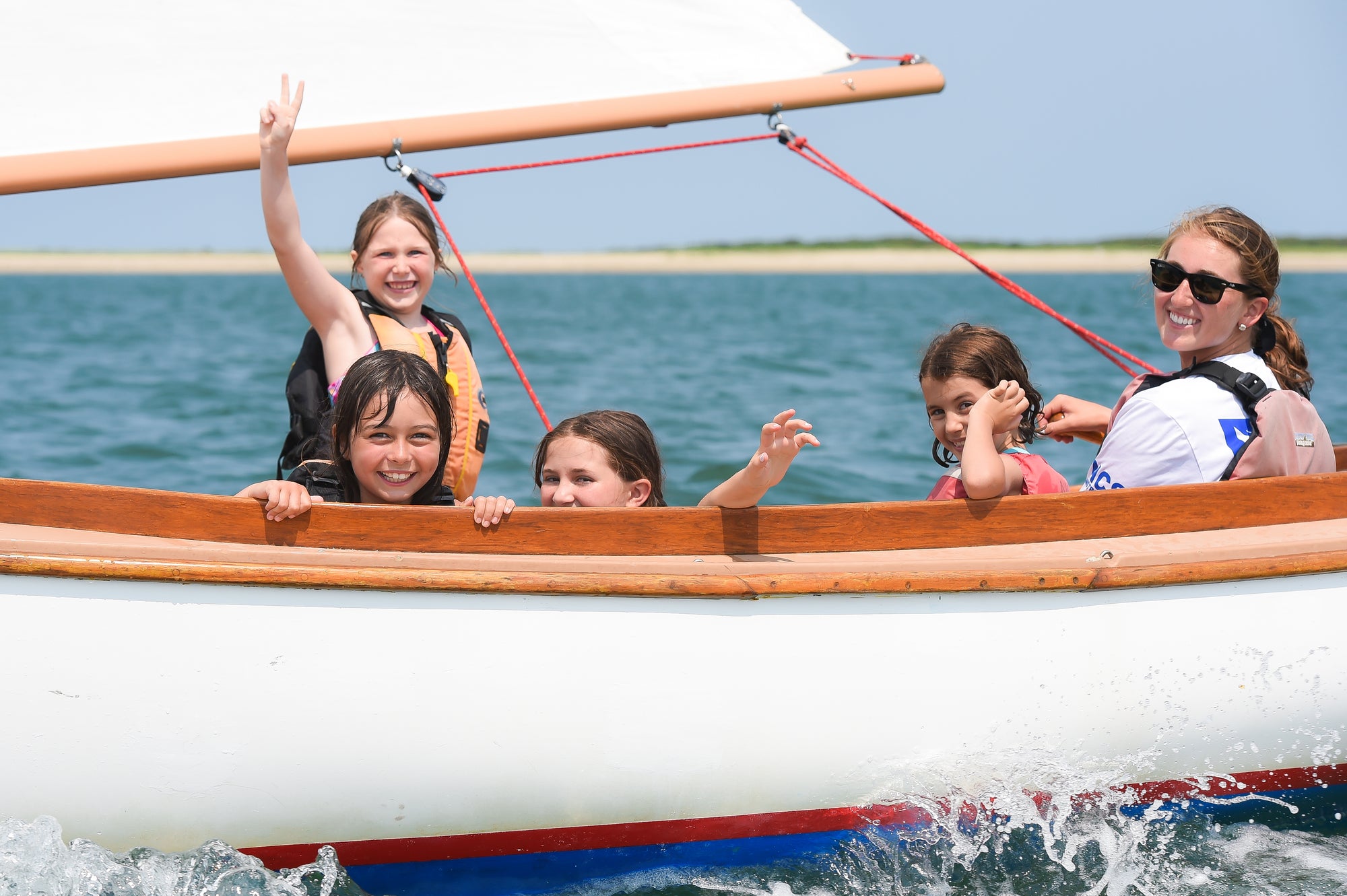 Children and a woman on a boat in the water with a clear sky.