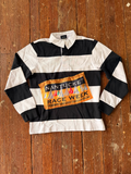 A long-sleeve rugby jersey with bold black and white stripes, featuring a yellow 'Nantucket Race Week' patch on the chest, laid flat on a rustic wooden surface.