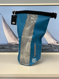 Blue dry bag with mesh side on a shelf in front of a sailboat image