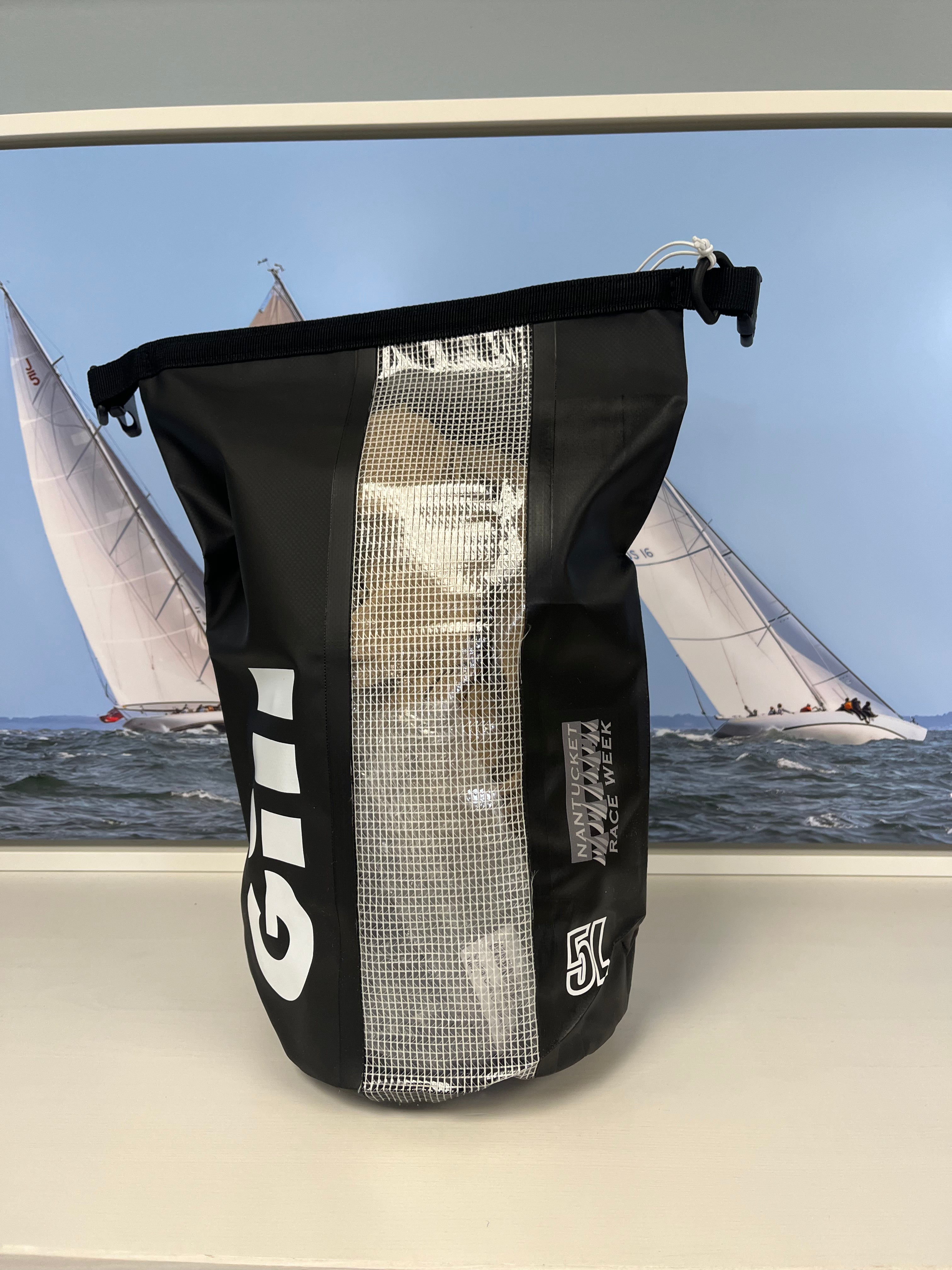 Black and white bag with visible branding in front of a sailing scene