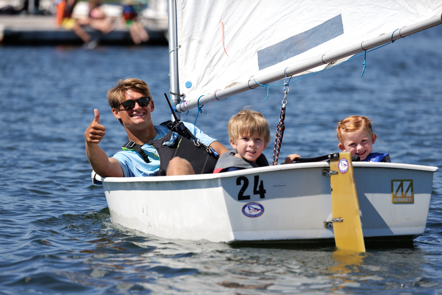 Instructor and two children in a small sailboat on water