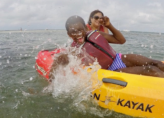 Two people in a yellow kayak on water with a cloudy sky.